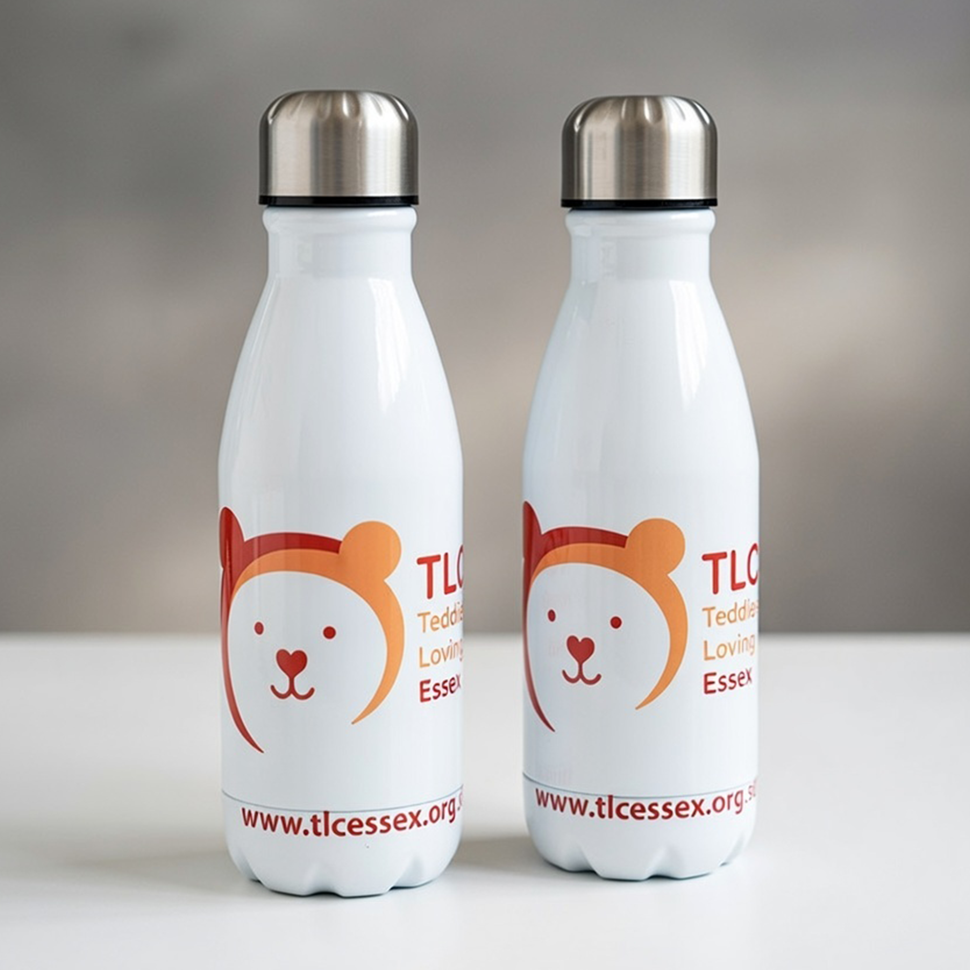 Two white aluminium drinks bottles printed with the TLC Essex logo